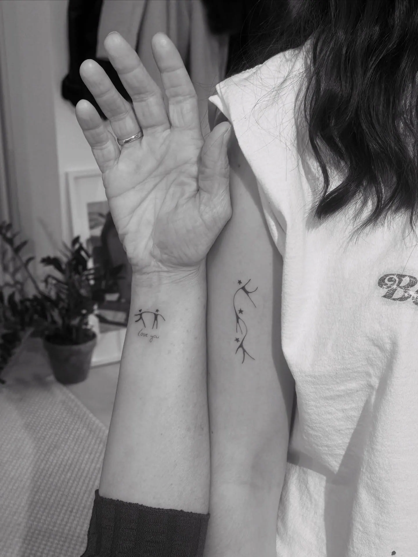 Zeichnung eines Kindes mit dem Schriftzug love you als Tattoo am Handgelenk der Mutter