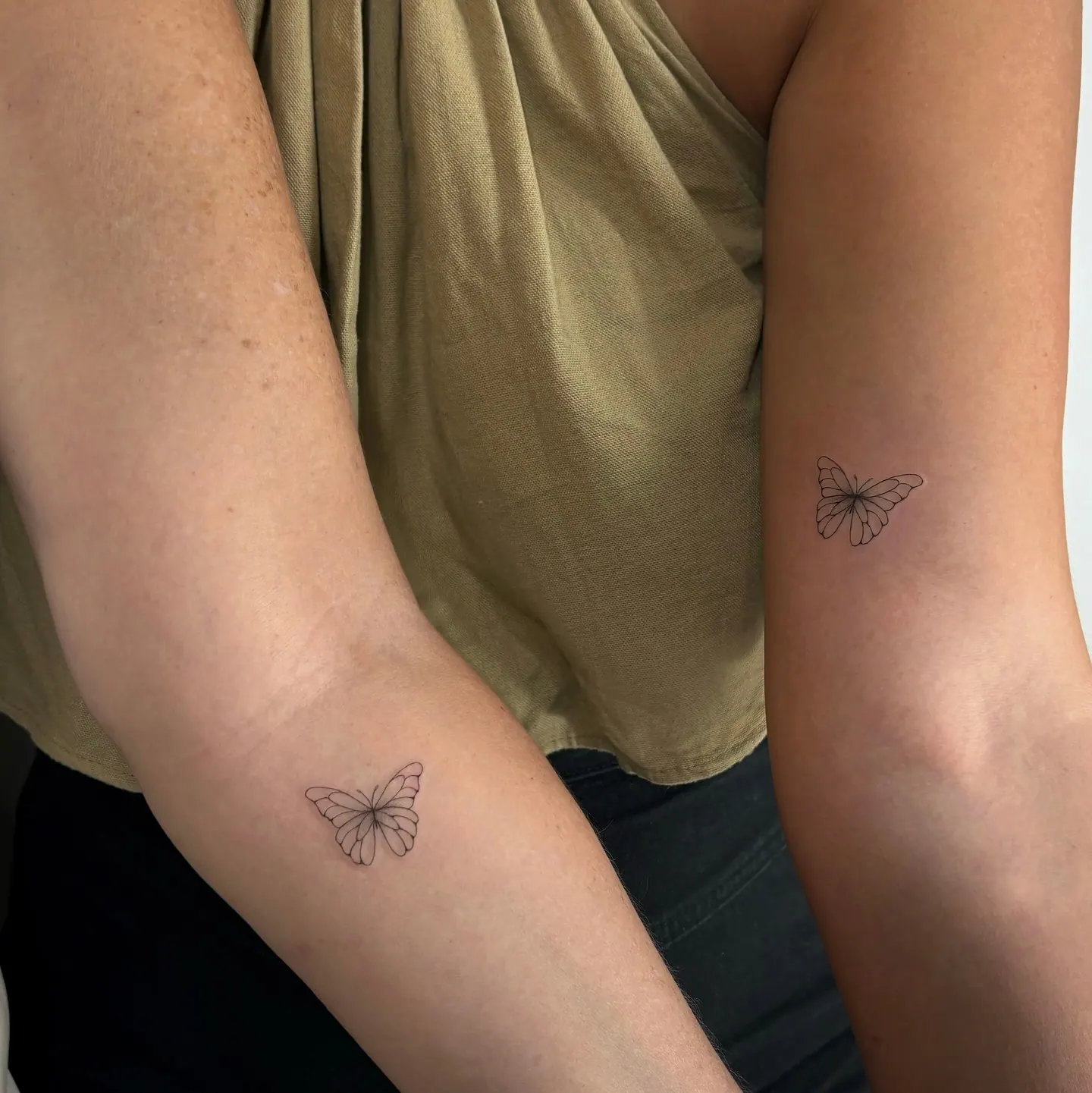 Zwei gleiche Fine Line Schmetterling Tattoos an zwei Armen